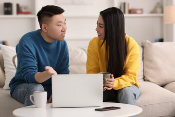 Happy couple spending time together and using laptop at home