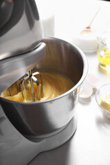 Making dough in bowl of stand mixer on white table, closeup