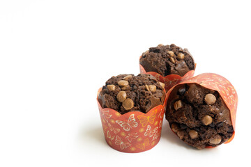 Three chocolate muffin isolated on a white background with copy space. Homemade fluffy and moist chocolate cakes.