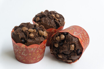 Three chocolate muffin isolated on a white background with copy space. Homemade fluffy and moist chocolate cakes.