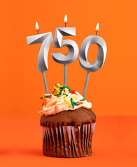 Birthday cupcake with number 750 candle - Orange color background