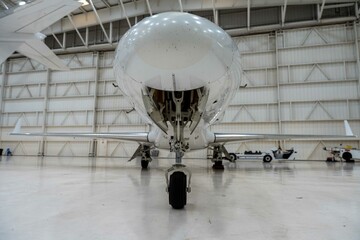 Low angle of a white private airplane in a maintenance hangar.