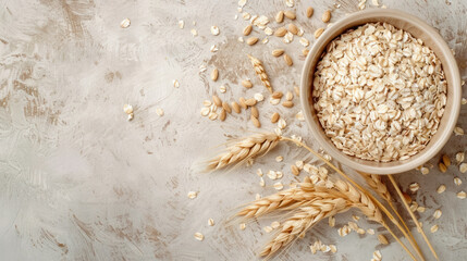 top view of organic oats in ceramic bowl with wheat ears on neutral background