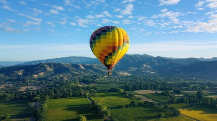 Obraz premium Hot air balloon over green fields under blue sky.