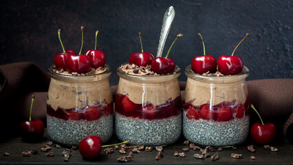 Three Black Forest chia puddings with chocolate mousse and fresh cherries.