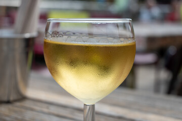 Tasting of Bordeaux white wine in Sauternes, left bank of Gironde Estuary, France. Glasses of white sweet French wine served in outdoor restaurant