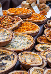 Tasty vegetarian streetfood for lunch in London, various quiche savoury tart swith spinach, tomatoes, mushrooms, cheddar cheese