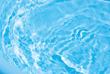 Blue water with ripples on the surface. Defocus blurred transparent blue colored clear calm water surface texture with splashes and bubbles. Water waves with shining pattern texture background.