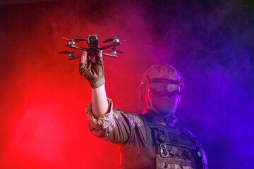 A soldier is depicted holding a drone while wearing stealth gear for military operations