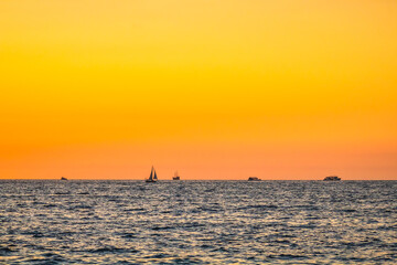 Sailboat and ship at sunset with the sun on the horizon in Puerto Vallarta Jalisco