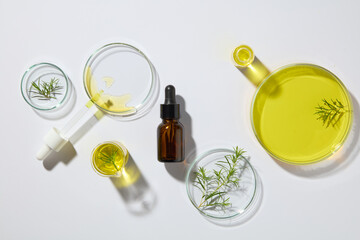 Blank label dropper bottle surrounded by several petri dishes filled with yellow liquid and tea...