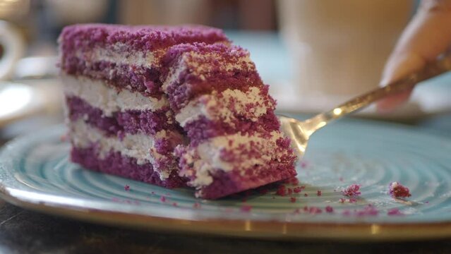 cutting A piece of purple velvet cake with cream 