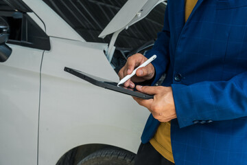 A businessman stands next to his damaged vehicle after an accident, holding a clipboard and examining the scene. An insurance agent arrives to assess the damage and start the claim process.