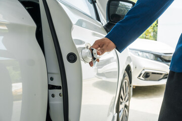 A businessman stands next to his damaged vehicle after an accident, holding a clipboard and examining the scene. An insurance agent arrives to assess the damage and start the claim process.