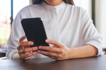 Closeup image of a woman holding and using mobile phone
