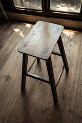 Old stool chair standing in a dark room near the window.
