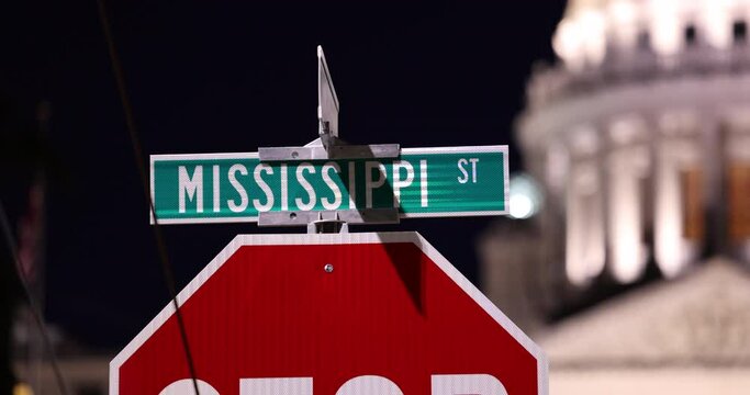 Jackson, Mississippi, USA - April 23, 2024: Artificial night light shines on the Mississippi Street sign and state capitol.