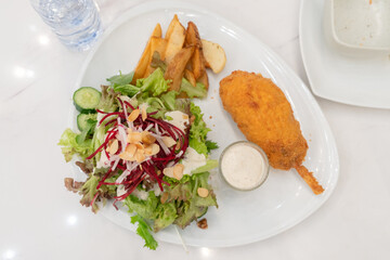 Top view of chicken Steak stuffed with cheese with mixed salad and french fries.
