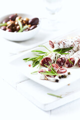 Sliced french salami with fresh rosemary on white background. Copy space.