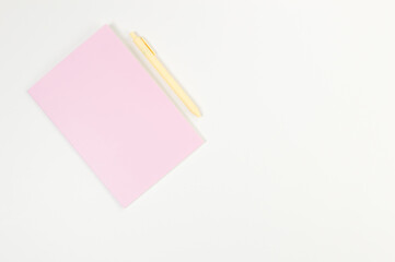 Top view of pink notebook, yellow pen on white background. School, office wallpaper. Flat lay, copy space.