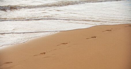 Footprints at golden sand, footsteps. Beach with golden sand, turquoise ocean water. Panoramic sea view. Natural background for summer vacation.