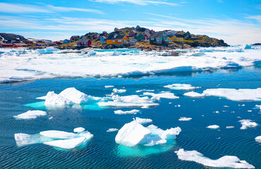 Panoramic view of colorful Kulusuk village in East Greenland - Kulusuk, Greenland - Melting of a iceberg and pouring water into the sea © muratart