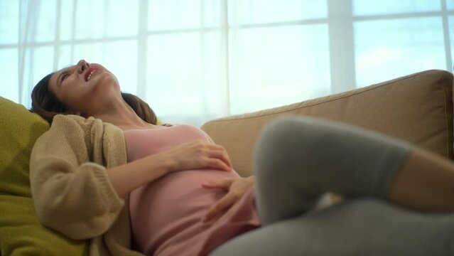 Young pregnant woman suffering from abdominal pain alone at home, female feel abnormal painful contraction during pregnancy, accidental medical urgency case and health care insurance for pregnancy.
