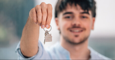 keys with house keychain in close-up in hand of happy young man