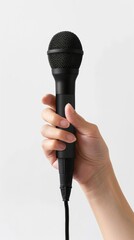 Hand holding a black microphone with white background, close-up. Music and performance concept