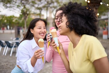 Smiling young multiethnic women enjoying ice cream together