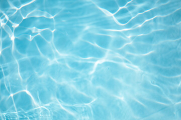 Blue water with ripples on the surface. Defocus blurred transparent blue colored clear calm water surface texture with splashes and bubbles. Water waves with shining pattern texture background.