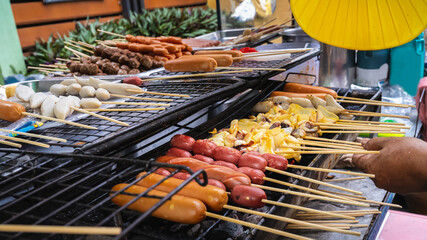 Simple street food in Bangkok, Thailand, meatballs, sausages, grilled squid on a stick With...