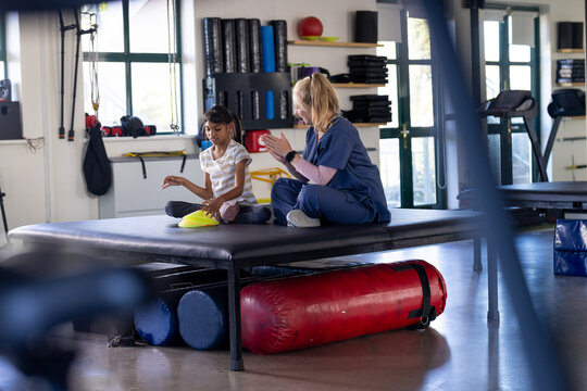 Assisting girl with cerebral palsy with physical therapy, female therapist in rehabilitation center