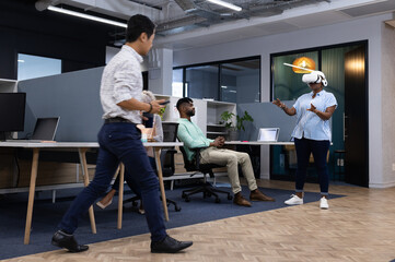 Using VR headset, female office worker demonstrating virtual reality to colleagues