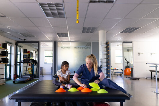 Assisting girl with cerebral palsy, female therapist working in rehabilitation center