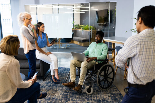 Group of business people in meeting, man in wheelchair using laptop for presentation