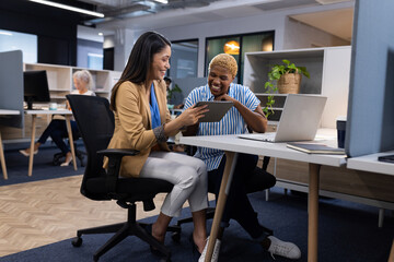 Collaborating in modern office, female showing tablet to male colleague