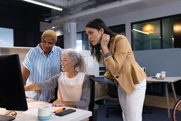 Team of businesswomen collaborating on computer project in modern office