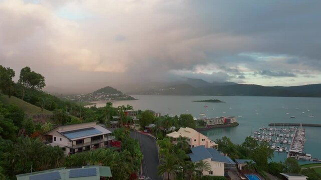 Port Airlie Beach Bay Lagoon Coral Sea marina aerial drone road cars towards Cannonvale pink yellow sunrise morning rain heart of Great Barrier Reef Whitsundays Whitehaven neighborhood forward motion