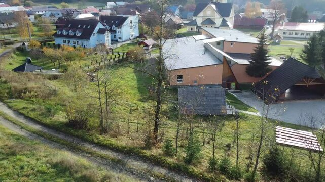 Drone view of mountain village with church and surrounding hills.