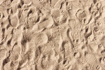 Various shoe prints on the surface of dry sand. View from above.