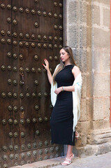 Beautiful Spanish woman from Seville dressed in an elegant black dress and a typical beige silk shawl with fringes embroidered with silk flowers. The shawl is Andalusian and has a flamenco air.