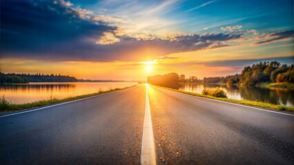 Naklejka premium Sunset Lake Road Blur: A serene blurred background of a lake and road at sunset, with the warm glow of the setting sun reflecting on the water. 