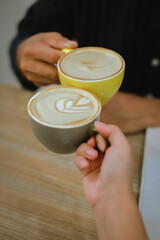 Close-up of a man and woman clinking white coffee cups in a coffee shop. While talking about business matters