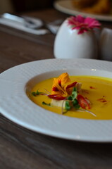 yellow vegetable soup with herbs, squid, pumpkin soup, herbs, plate, serving restaurant table, lunch menu 