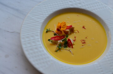 yellow vegetable soup with herbs, squid, pumpkin soup, herbs, plate, serving restaurant table, lunch menu 
