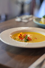 yellow vegetable soup with herbs, squid, pumpkin soup, herbs, plate, serving restaurant table, lunch menu 