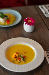 yellow vegetable soup with herbs, squid, pumpkin soup, herbs, plate, serving restaurant table, lunch menu 