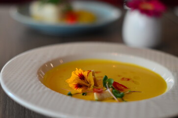 yellow vegetable soup with herbs, squid, pumpkin soup, herbs, plate, serving restaurant table, lunch menu 