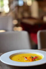 yellow vegetable soup with herbs, squid, pumpkin soup, herbs, plate, serving restaurant table, lunch menu 